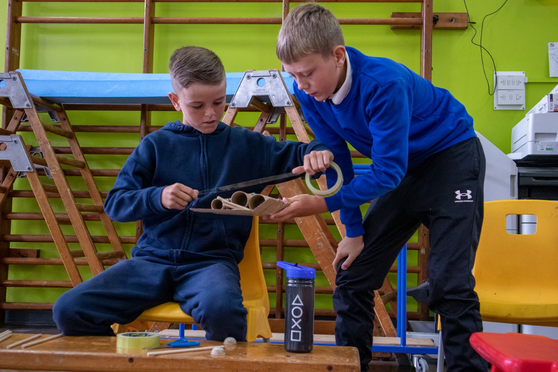 two boys building a cardboard bridge