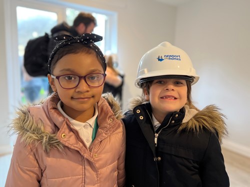 two girls , one wearing a hard hat
