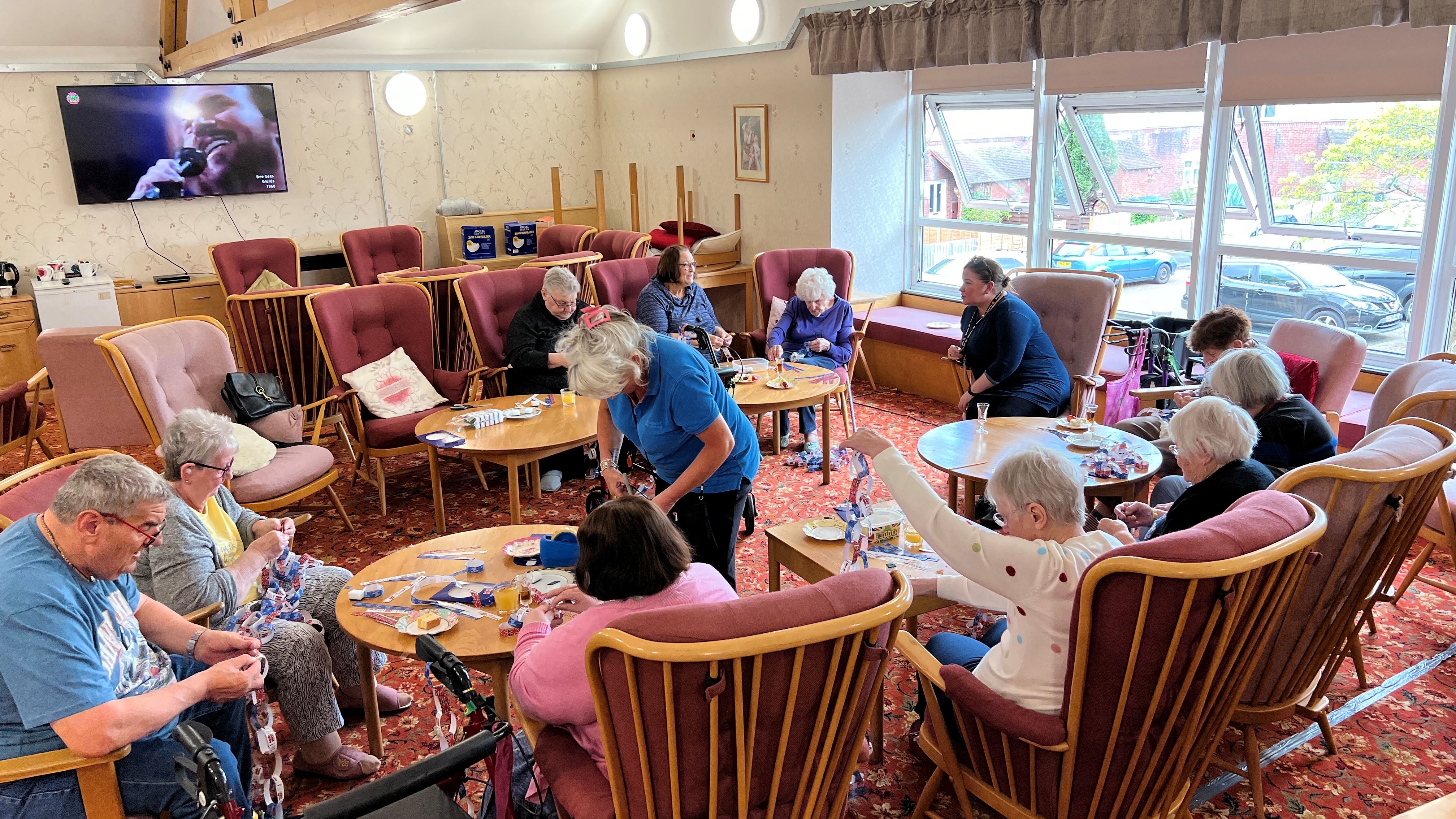 a group of older people sat in a communal lounge doing an arts activity