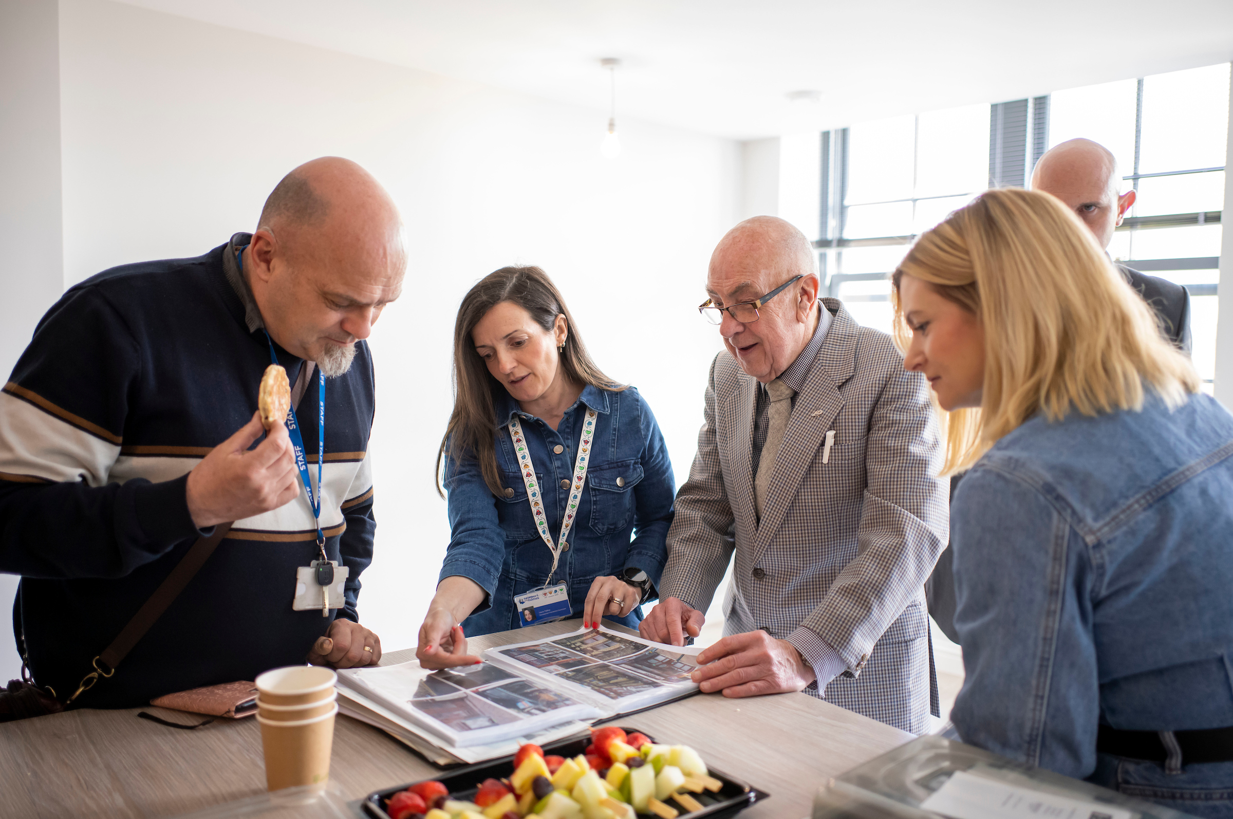 four people look at a photo album