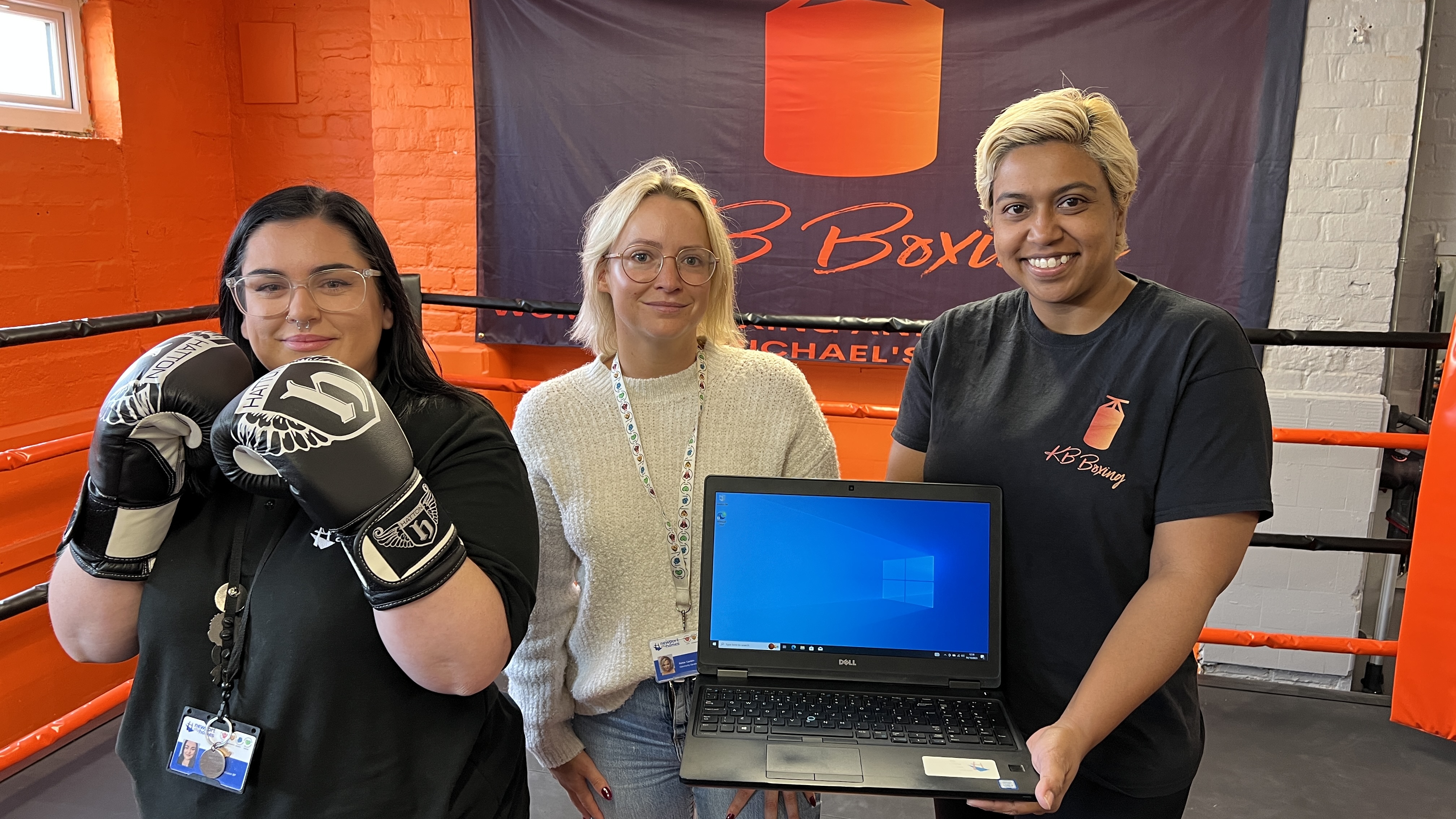 three women in a boxing gym- one is holding a laptop