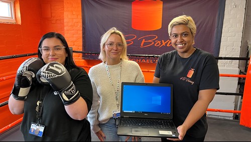 three women in a boxing gym- one is holding a laptop